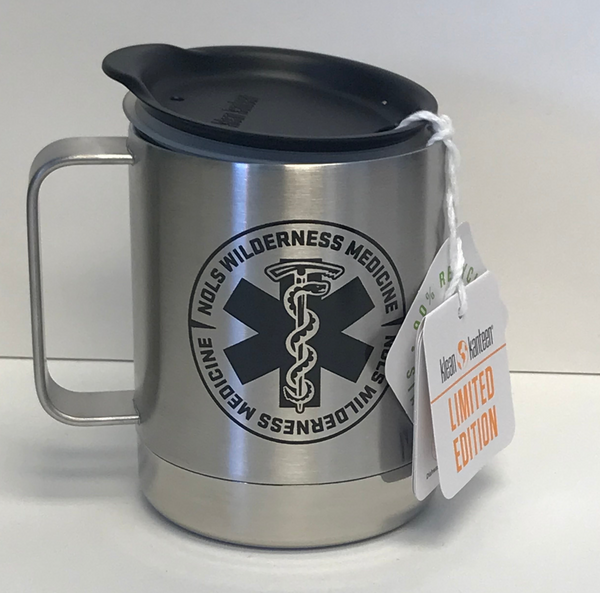 Klean Kanteen Wilderness Medicine Camp Mug in brushed stainless steel with black medical star of life logo, featuring splash-proof lid and sturdy handle. Limited edition tag attached. 12 oz insulated mug shown against white background.